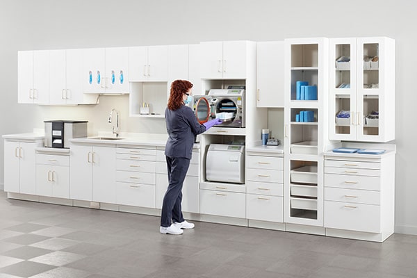 View of a sterilization room with a dental assistant using an autoclave.